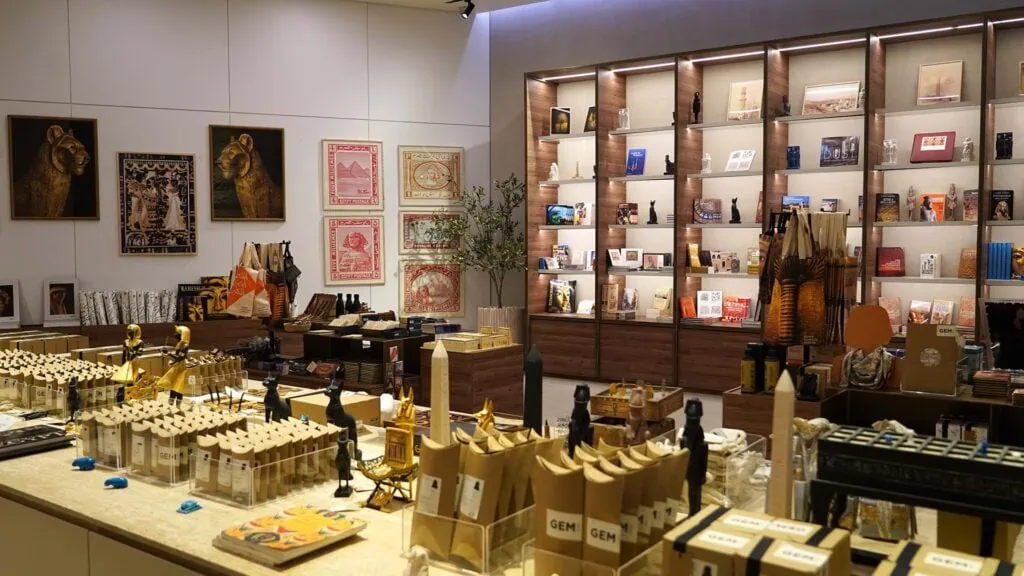 Luxury gift shop with Egyptian jewelry displays, statues, and artwork on shelves and counters.